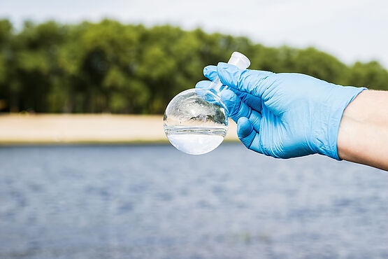 WESSLING Mitarbeiter hält Wasserprobe im Gefäß in der Hand